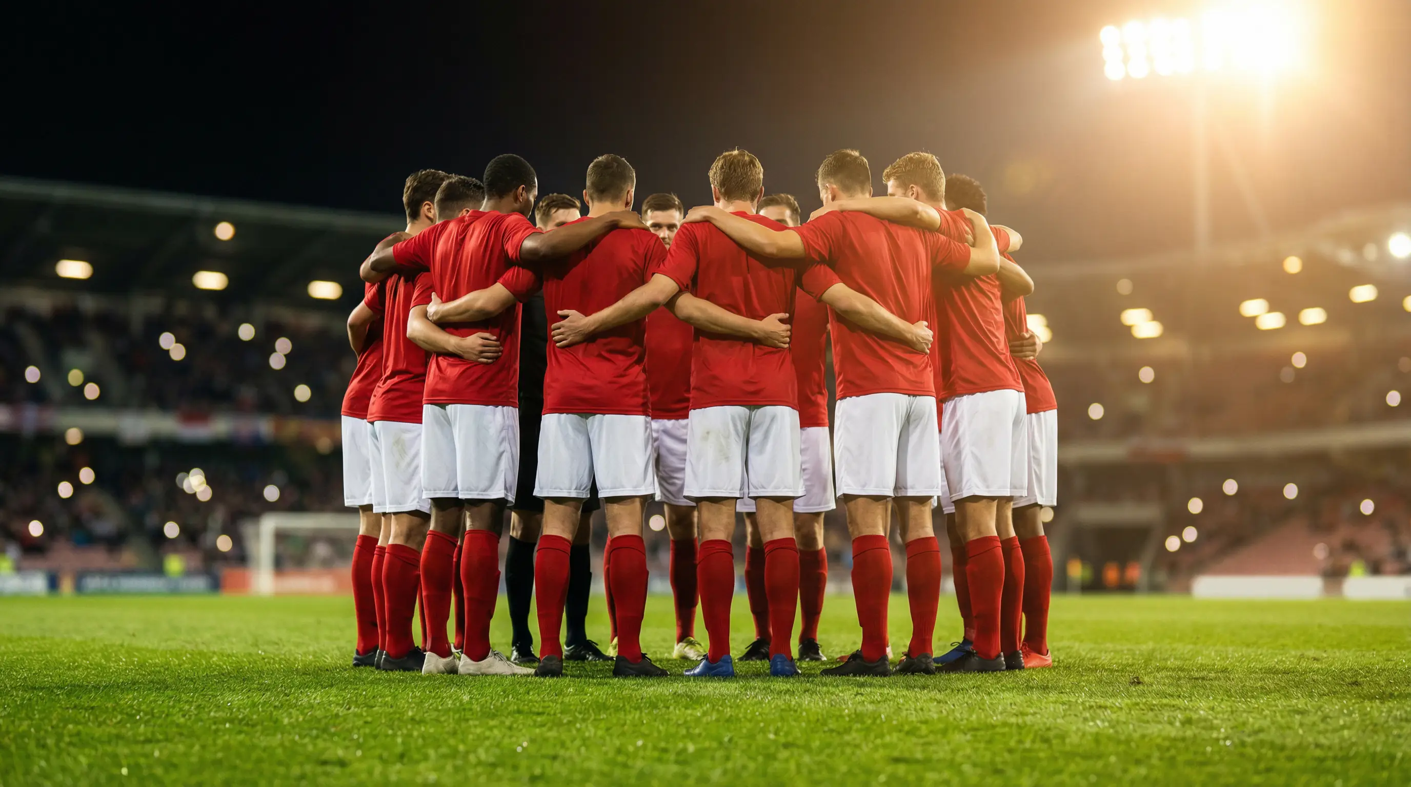 Voetbalspelers in rode shirts op het veld tijdens een interland onder stadionverlichting